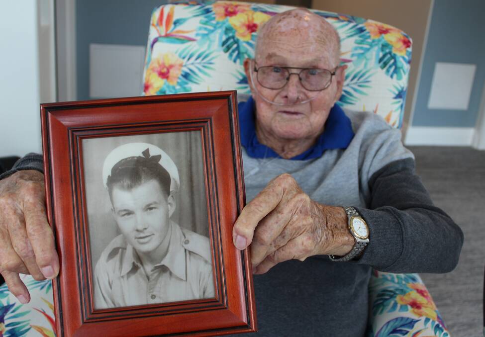 Brian Beames holds a photo of himself taken during World War II.
