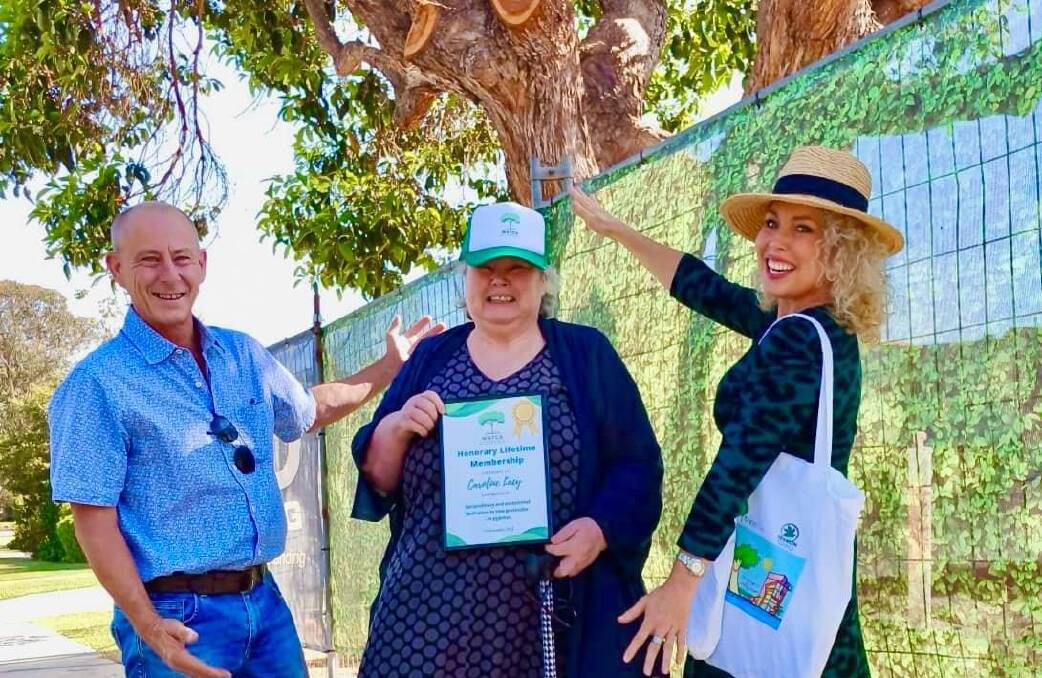 Caroline Lacy, by the verge tree she saved, shows off her certificate from tree advocates Nick Cook and Sarah Allchurch. Picture supplied