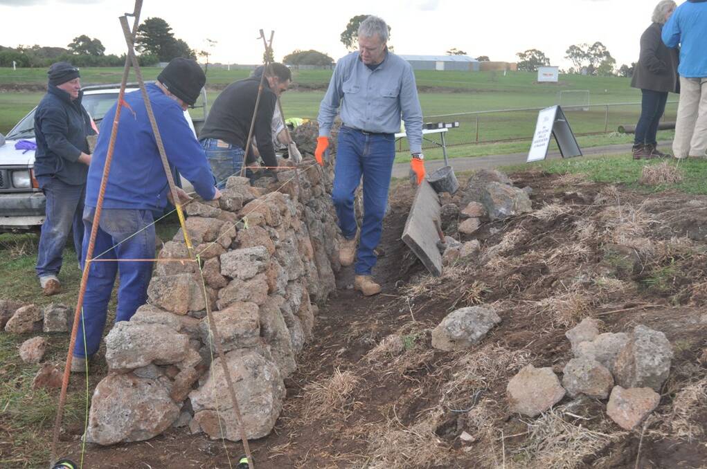 ALL IN PLACE – Professional dry stone wallers David Long (right) and Alistair Tune (centre) put the finishing touches to the wall at Camperdown showgrounds assisted by John Chapman (left).